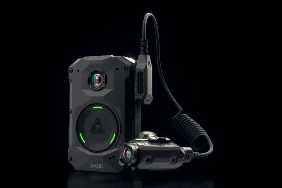 An Axon Body 4 camera with the optional POV camera on its cable, against black