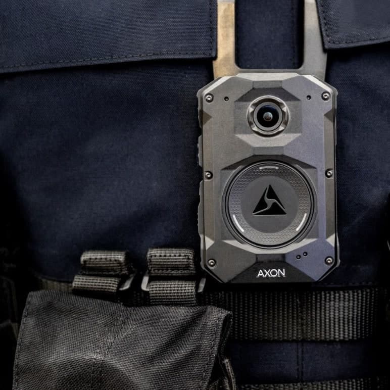 An Axon Body 4 camera worn on a uniform vest, from the front